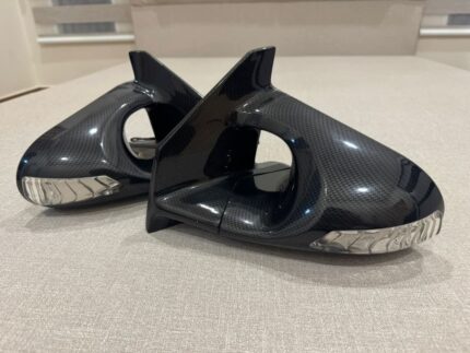 Carbon fiber aero side mirrors featuring integrated turn signal indicators, styled in the iconic Ganador Super Mirror design.