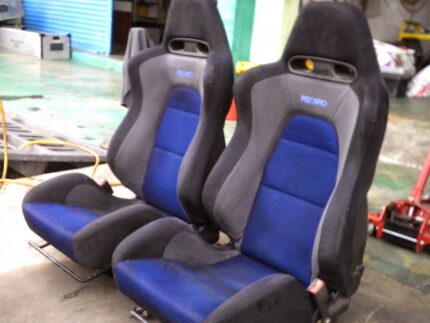 OEM blue and black Recaro front and rear interior seats from a Mitsubishi Lancer Evolution VII (CT9A), featuring blue mesh centers and black suede-like bolsters.