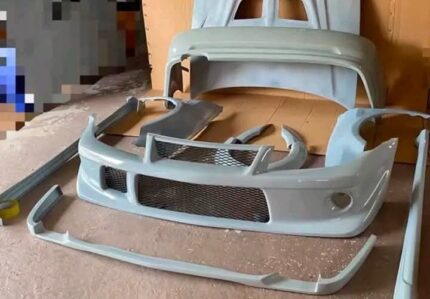 Custom fiberglass (FRP) body kits for Mitsubishi Lancer Evolution VI, featuring a primed front bumper with mesh inserts, side skirts,hood,side fenders,front bumper lip and a rear bumper component.